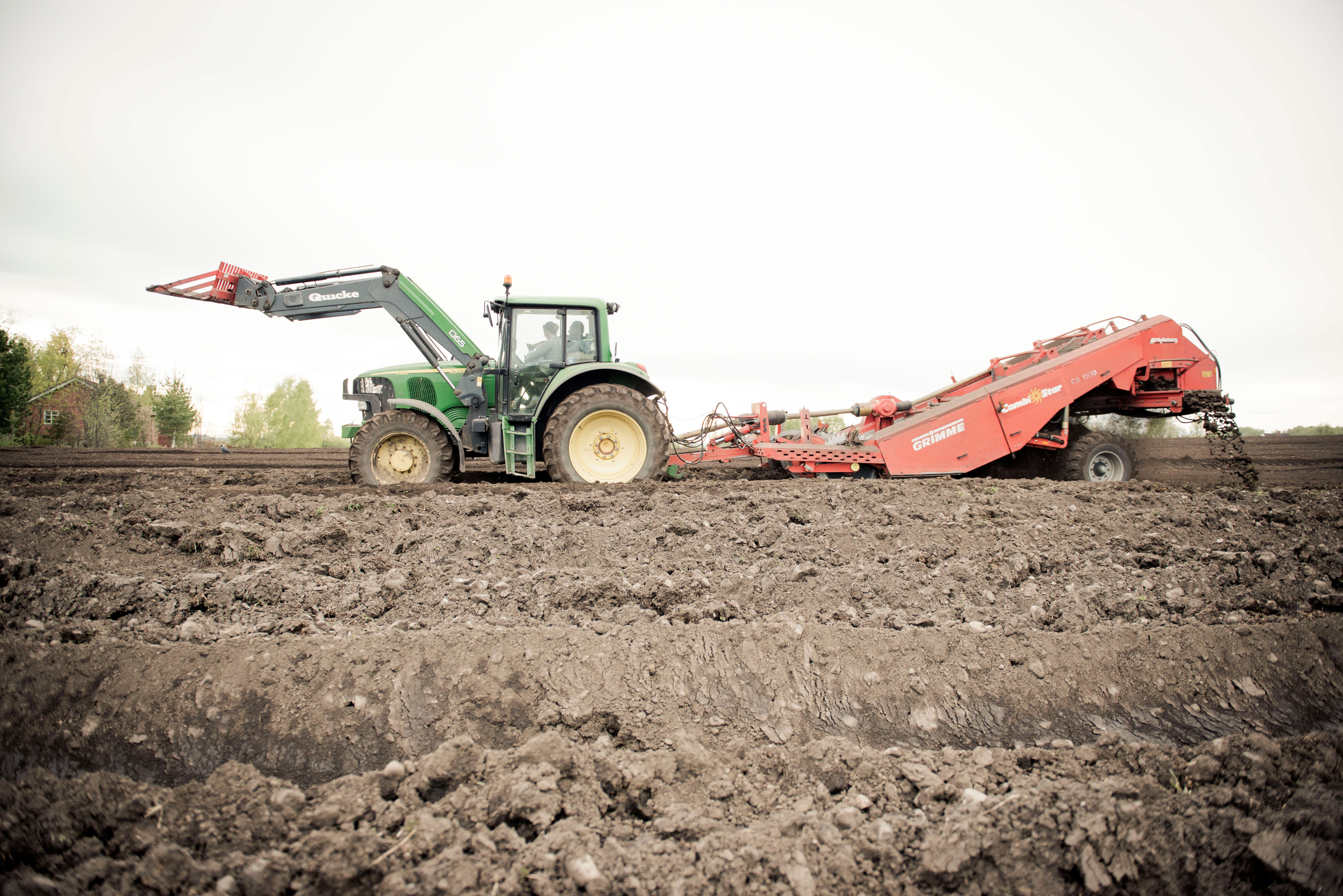 Traktor med potetmaskin på jordet. foto